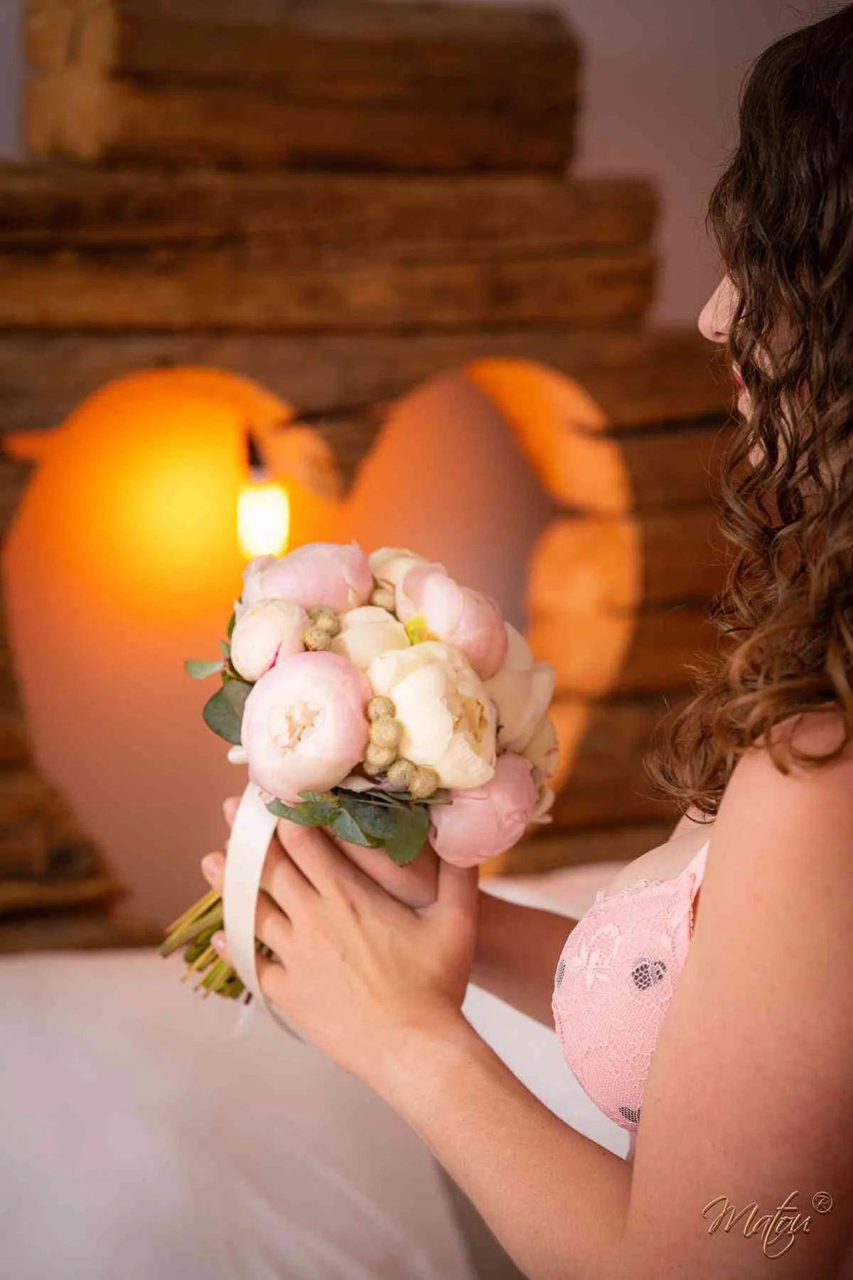 Femme tenant un bouquet de fleurs devant un décor lumineux en forme de cœur