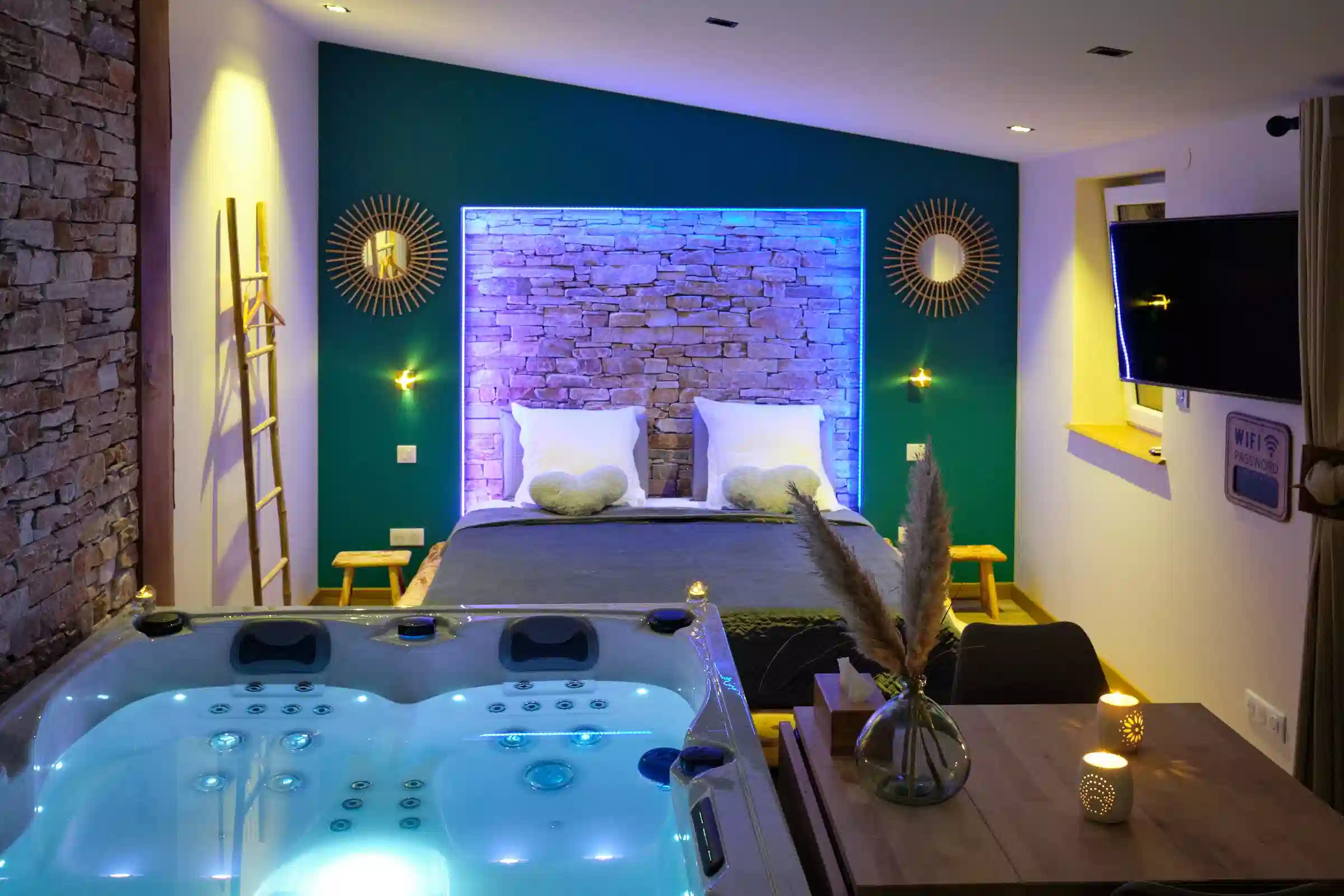 Jacuzzi éclairé face au lit de la love room Toy pour une nuit romantique
